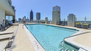 Ein Pool auf dem Dach mit Blick auf die Stadtlandschaft, Liegestühle und eine Tiefenmarkierung von 1,70 Metern.