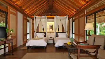 A room with two beds, a TV, a table with fruit, and a chair.