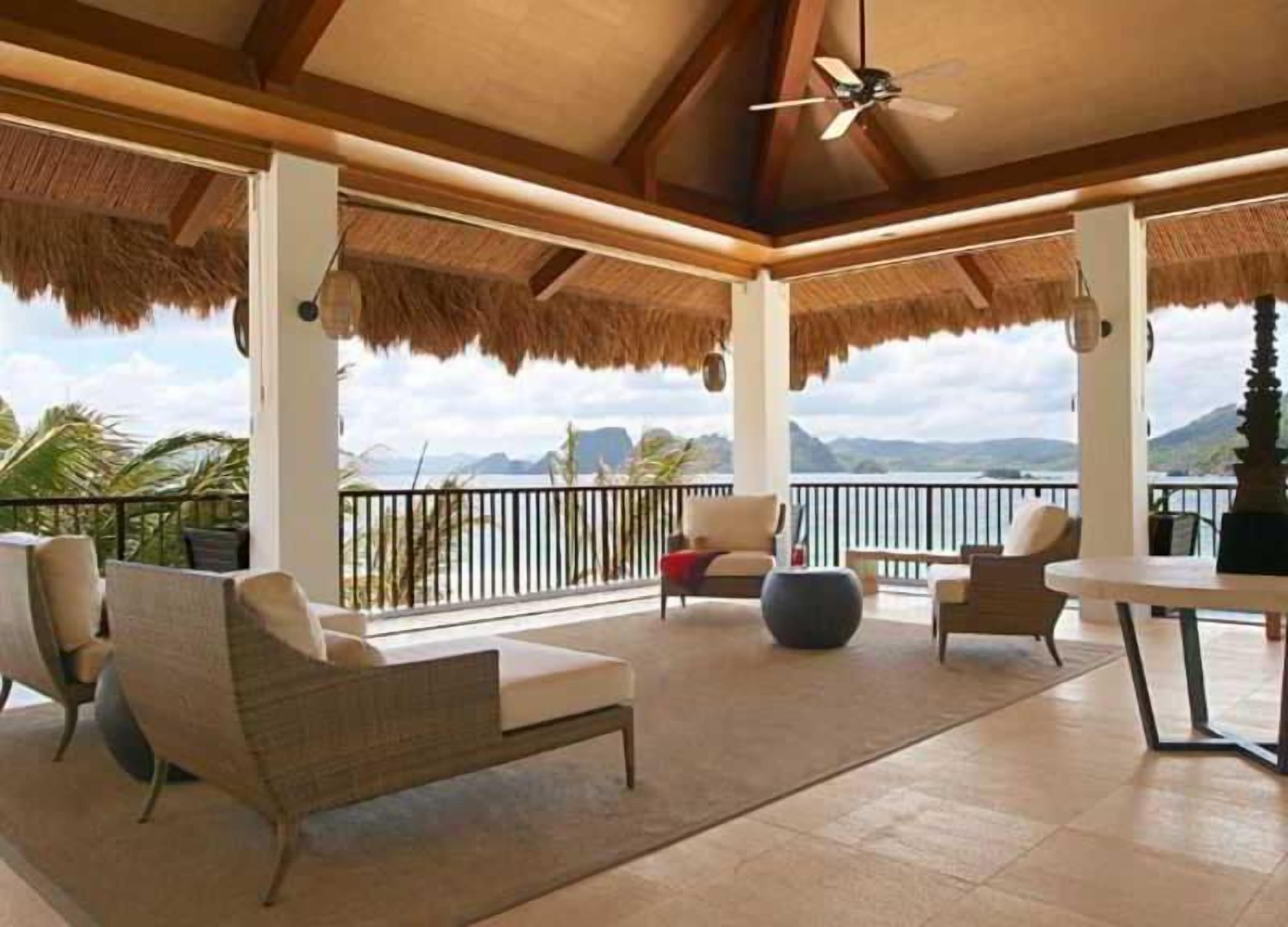 A covered outdoor seating area with chairs and a table, overlooking a scenic view.