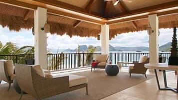 A covered outdoor seating area with chairs and a table, overlooking a scenic view.