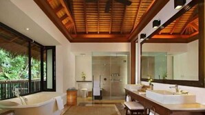 Ein modernes Badezimmer mit einer großen Badewanne, zwei Waschbecken, einem großen Spiegel und einer Duschkabine aus Glas.