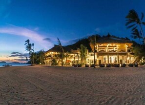 A beachfront hotel with multiple levels, outdoor seating, and palm trees. - El Nido Resorts Pangulasian Island (El Nido)