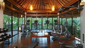 Ein Fitnessstudio mit Laufbändern, Crosstrainern und Kurzhanteln, ausgestattet mit großen Fenstern und einer Holzbalkendecke.
