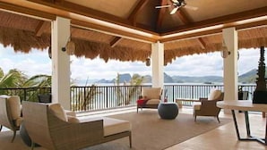 A covered outdoor seating area with chairs and a table, overlooking a scenic view.