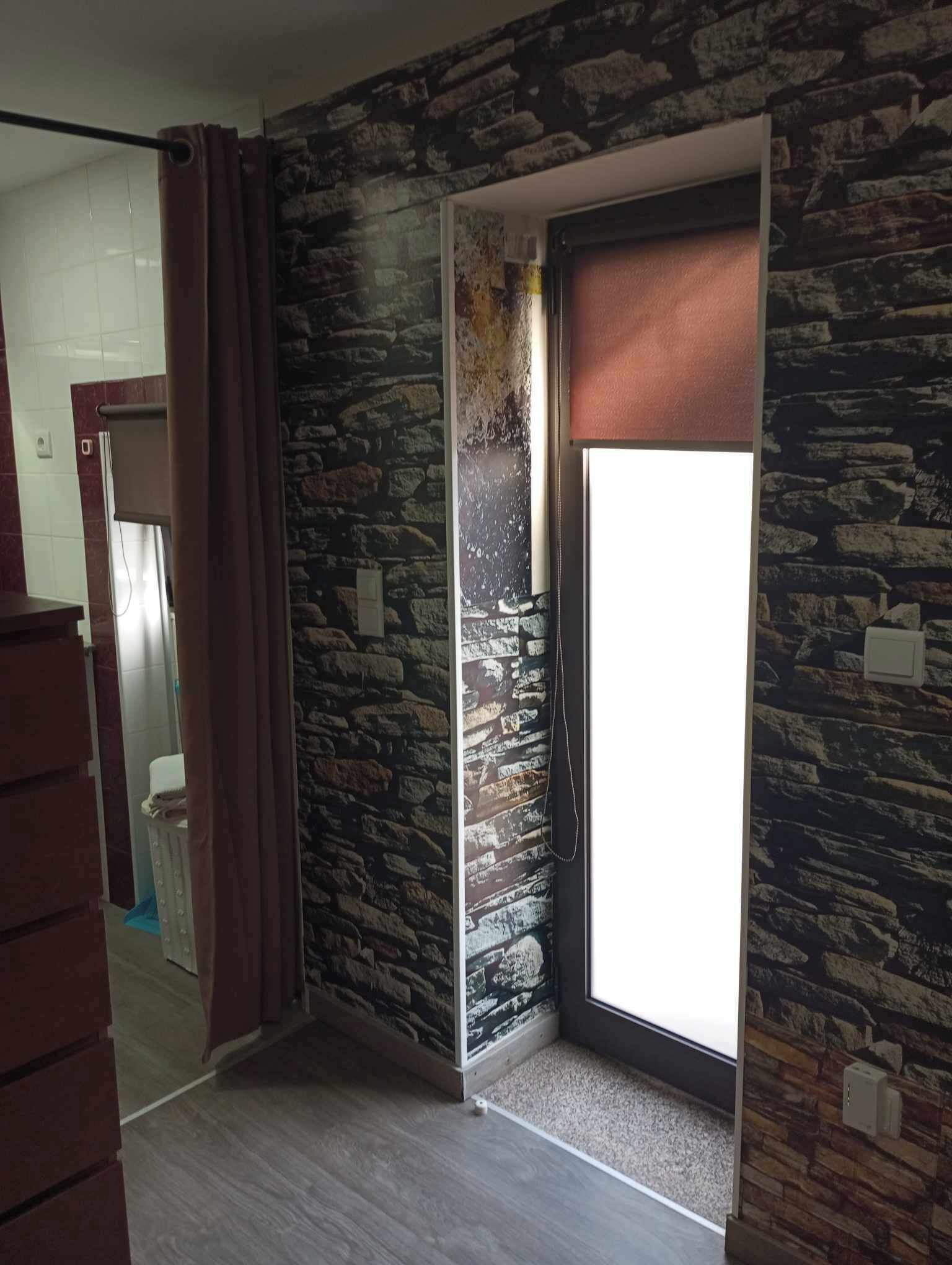 A room with a stone wall, a sliding door, and a wooden floor.