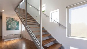 A modern staircase with glass railings and wooden steps, leading to a balcony with a view. - Bayside Retreat - Bay Views in Walkable Coronado (Coronado)