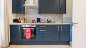 Eine moderne Küche mit dunkelblauen Schränken, einer weißen Arbeitsplatte und einem Edelstahlbackofen.