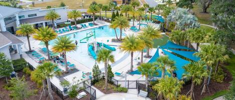 Vista aérea de un complejo turístico con varias piscinas, palmeras y un césped bien cuidado.