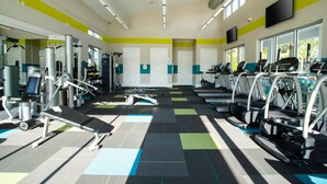 Een sportschool met diverse fitnessapparaten, waaronder loopbanden en krachtapparaten, netjes opgesteld in rijen.