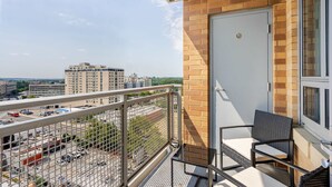Un balcone con vista su un parcheggio e edifici, una porta e una sedia.