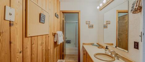 A wooden-paneled bathroom with a large mirror, a sink, and a towel rack.