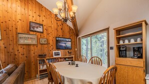 A wooden interior with a dining table, chairs, a bookshelf, and a coffee station. - Sans Souci 1 3 Bedroom Ski In, Ski Out Retreat (Whitefish)