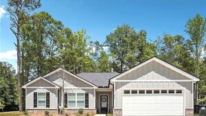 Une maison à deux étages avec un garage, un porche à l’avant et une pelouse bien entretenue.