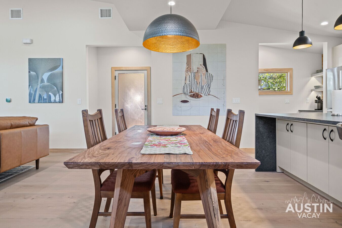 A dining area with a wooden table, six chairs, and a large pendant light.