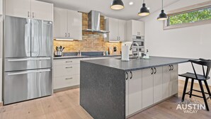 A modern kitchen with stainless steel appliances, a central island, and pendant lighting.