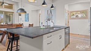 A modern kitchen with a central island, pendant lighting, and a view of the dining area.