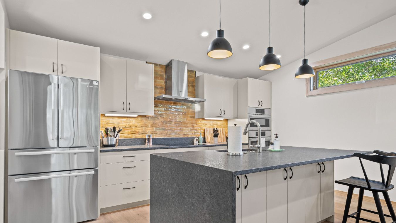 A modern kitchen with stainless steel appliances, a central island, and pendant lighting.