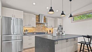 Una cucina moderna con elettrodomestici in acciaio inossidabile, un'isola centrale e luci a sospensione.