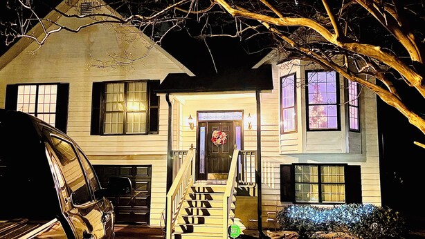 A two-story house with a front porch, a staircase, and a garage. - Cozy 1-bedroom house in welcoming Stone Mountain with AC (Stone Mountain)