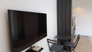 Un salon moderne avec un téléviseur à écran plat, une petite table ronde et deux chaises.
