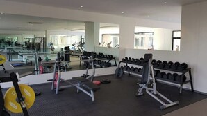 Une salle de sport équipée de matériel de musculation, de miroirs et d’haltères.