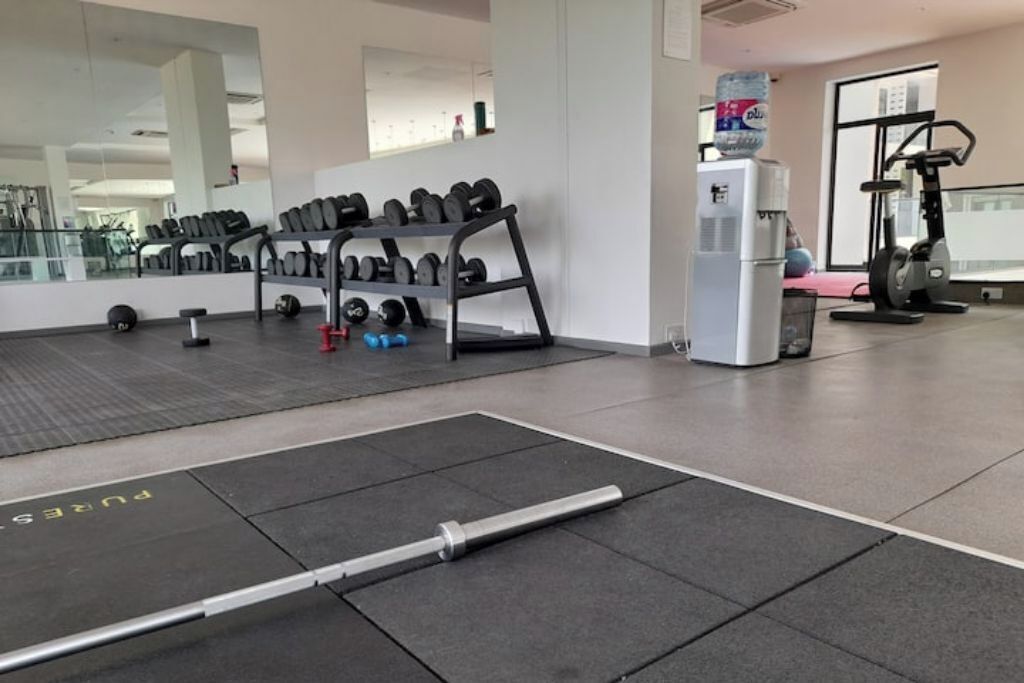 Un gimnasio con equipo de ejercicio, dispensador de agua y espejo.