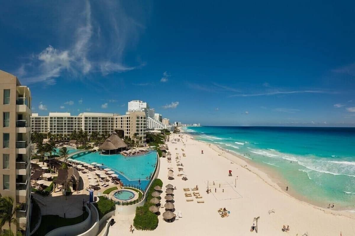 A resort with a large pool, beach, and ocean view.