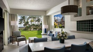 A modern hotel room with a dining area, a sofa set, a TV, and a view of a tropical garden. - Westin Lagunamar Ocean Resort & Spa (Cancún)
