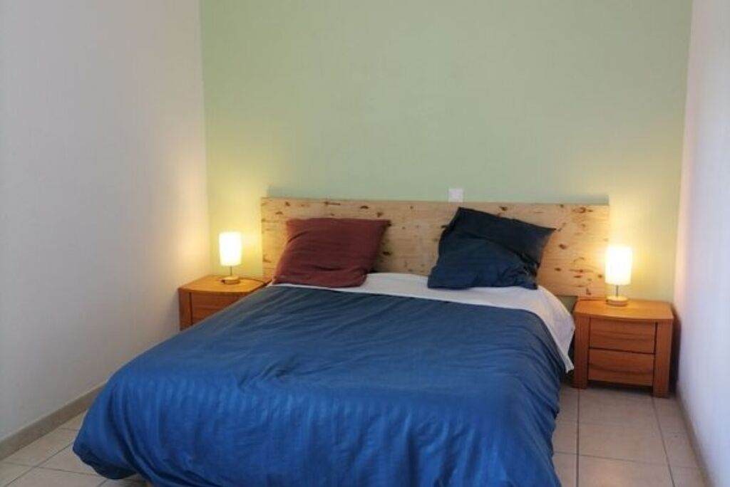 Een slaapkamer met een bed, twee nachtkastjes en twee wandlampen.