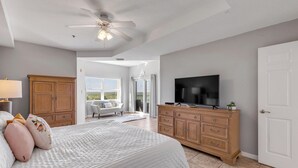 Une chambre à coucher avec un lit, une télévision, une commode et un ventilateur de plafond.