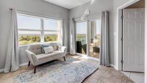 Une pièce spacieuse avec une grande fenêtre, un canapé et un tapis à motifs.