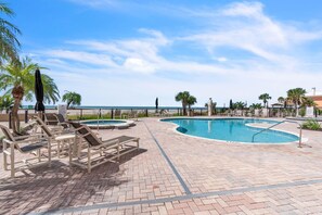 A pool area with lounge chairs and a hot tub.