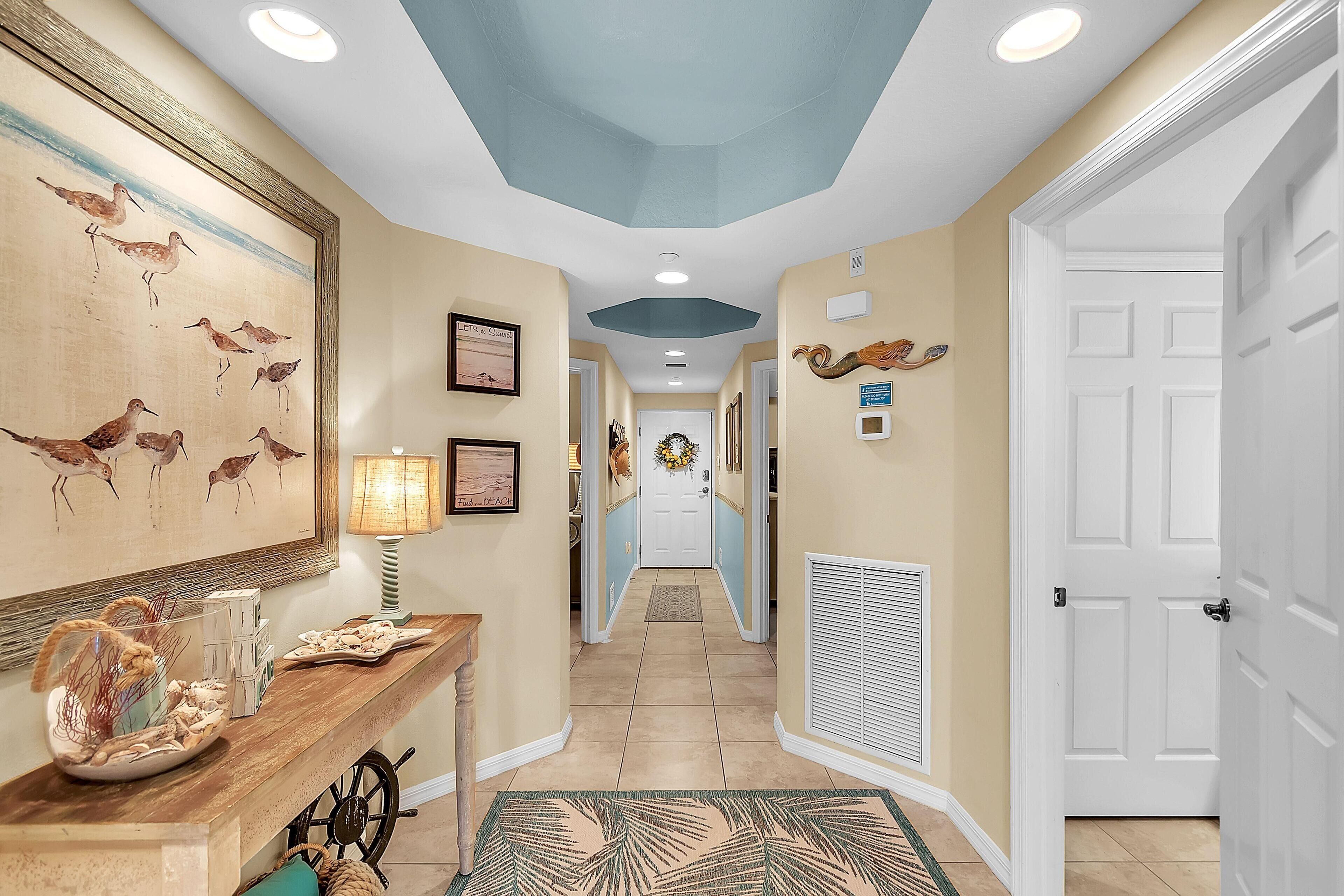 A hallway with a wooden console table, framed artwork, and a decorative rug.