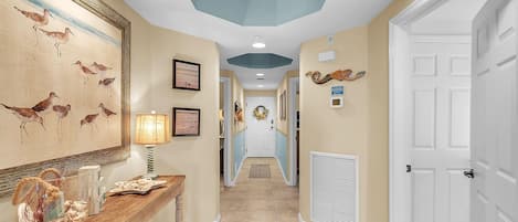 A hallway with a wooden console table, framed artwork, and a decorative rug.