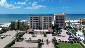 Un hotel de varios pisos con un patio central, estacionamiento y vista a la playa.