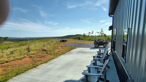 Un patio de concreto con asientos exteriores y vistas a un sendero de grava que conduce a un vehículo.