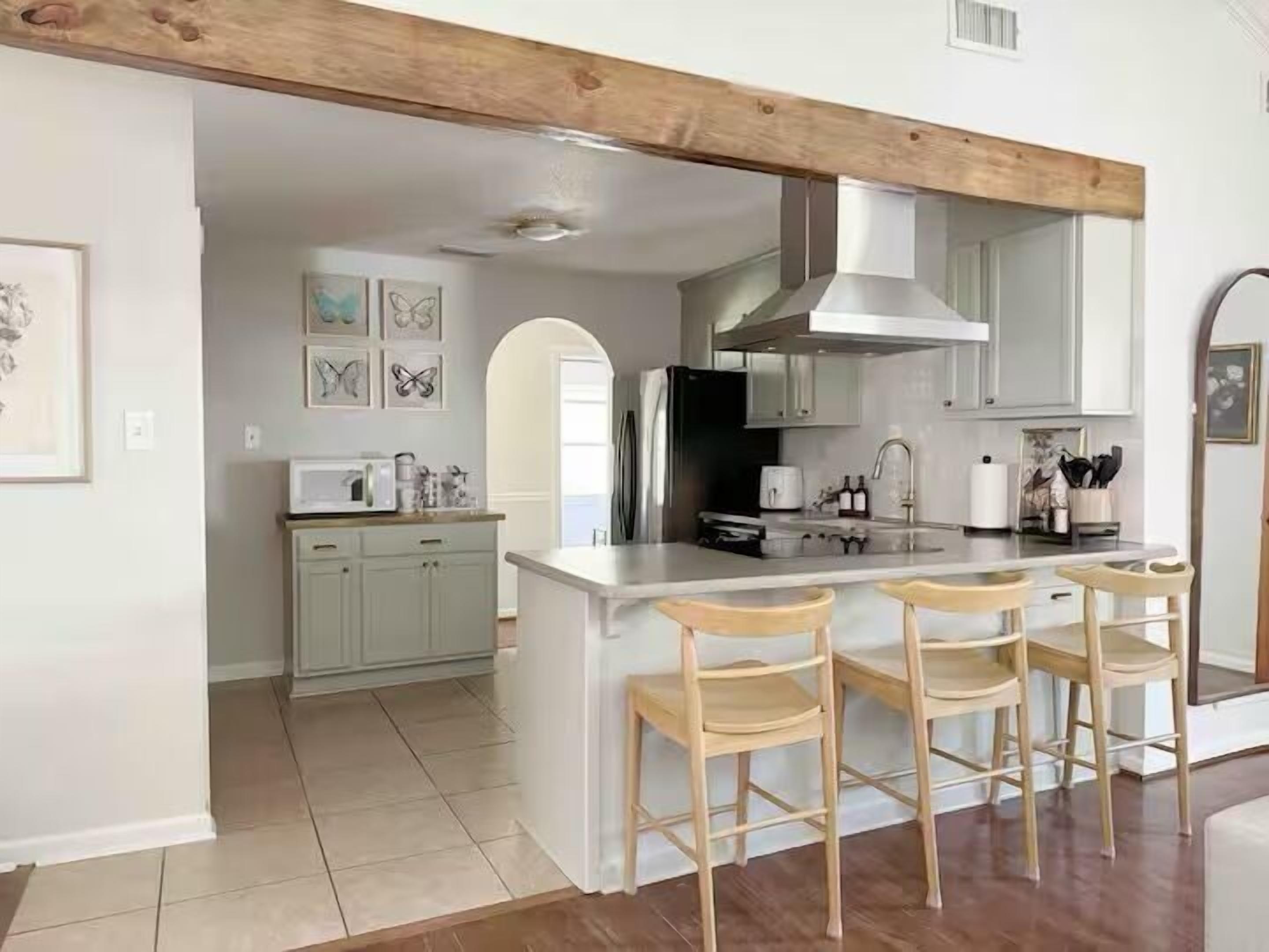 Una cocina moderna con una isla central, taburetes de bar y una viga de techo de madera.