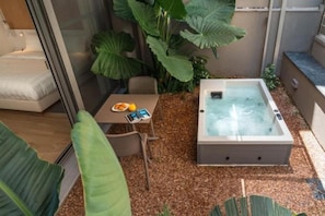 Un espace de détente extérieur moderne, doté d’un jacuzzi, de sièges et d’une table sur laquelle est disposé un panier de fruits.