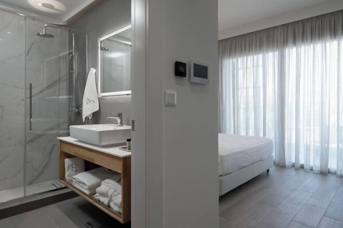 A modern bathroom with a glass shower, a white sink, and a wooden vanity.
