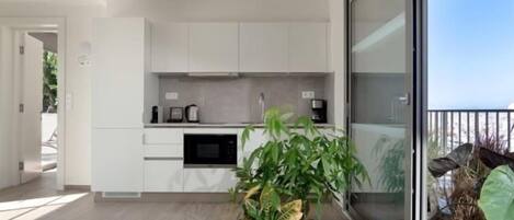 A modern kitchen with white cabinets, a built-in oven, and a large window.