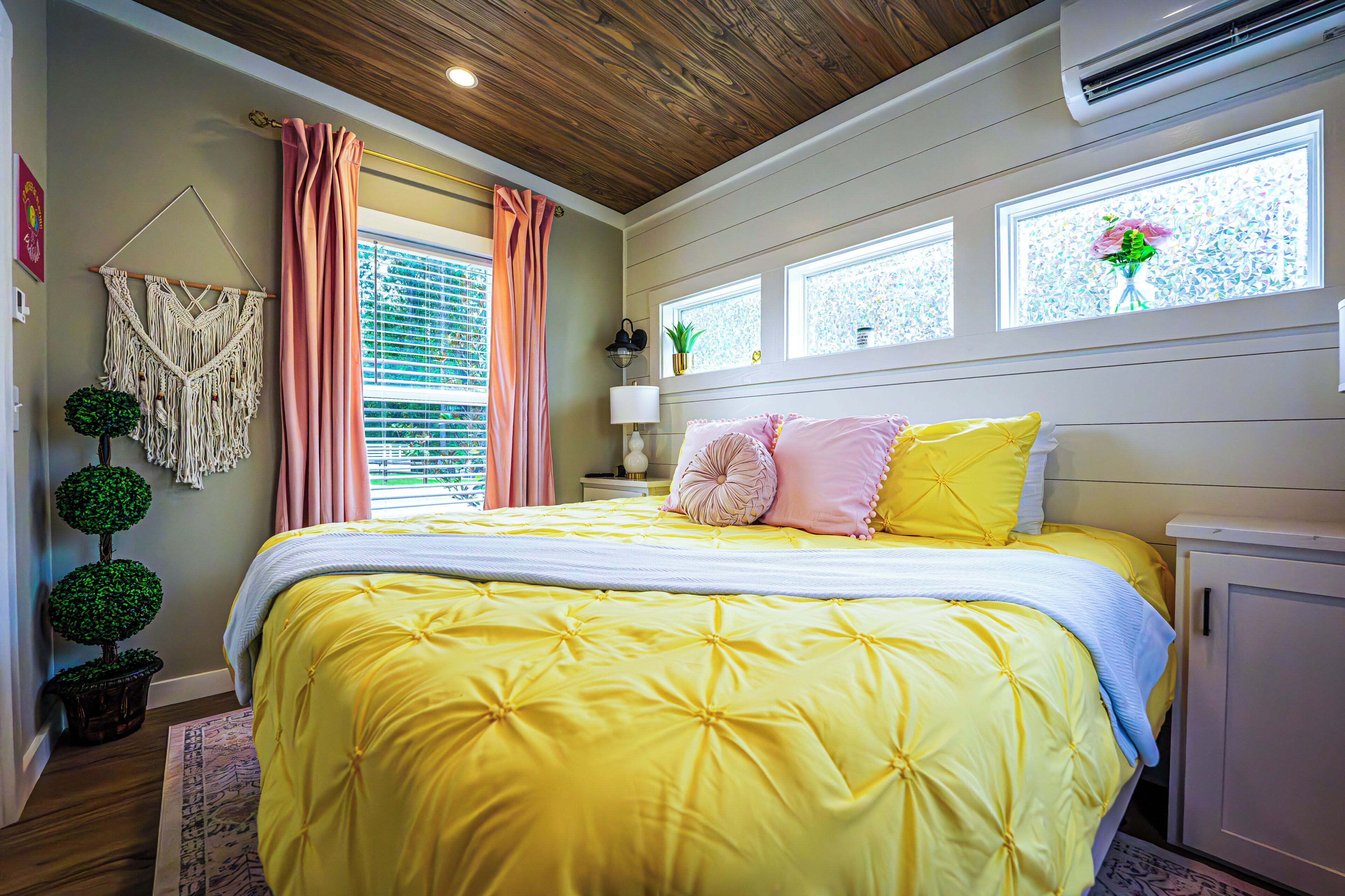 A bedroom with a large bed, a wooden ceiling, and a window with a view.