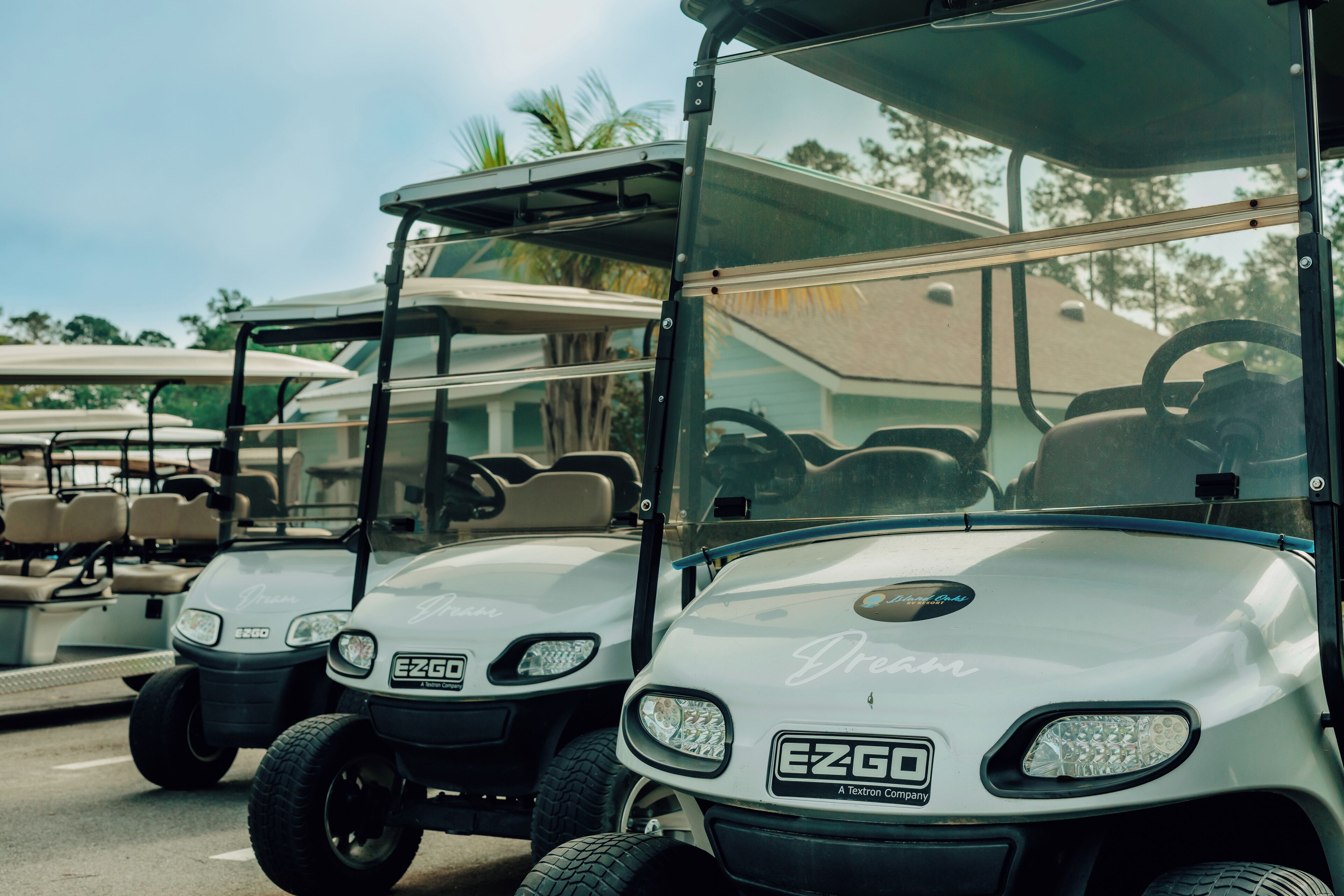 Tre golf cart parcheggiate in fila, ognuna con il marchio e il logo ben visibili.