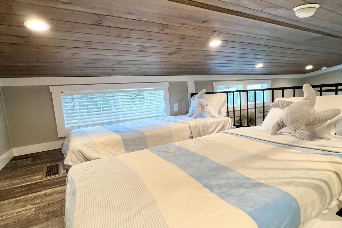 A bedroom with two beds, wooden flooring, and a sloped ceiling.