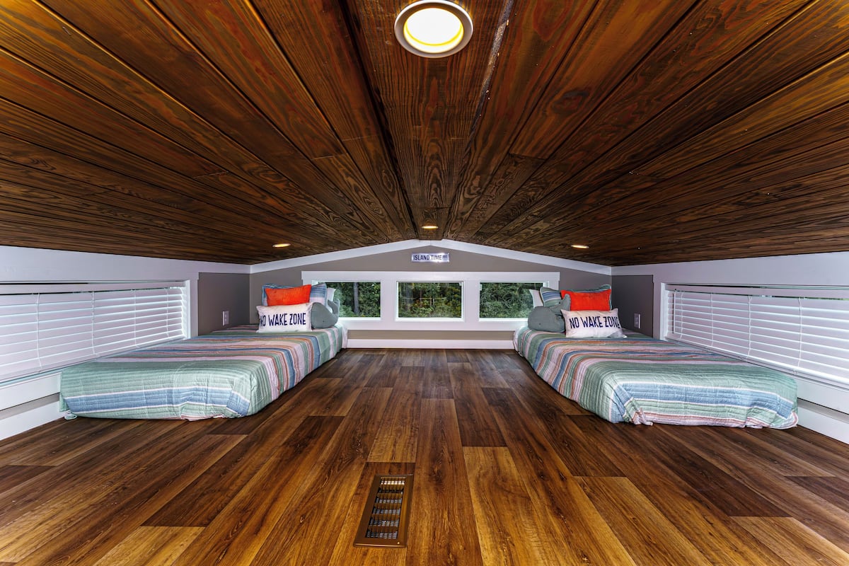 A room with two beds, a skylight, and a view of the outdoors.