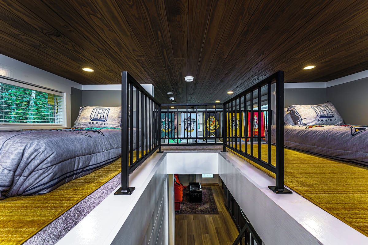 A room with two beds, a wooden ceiling, and a view of a balcony.