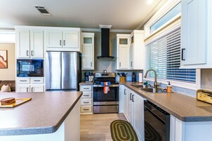Una cocina moderna con armarios blancos, electrodomésticos de acero inoxidable y encimera de granito.
