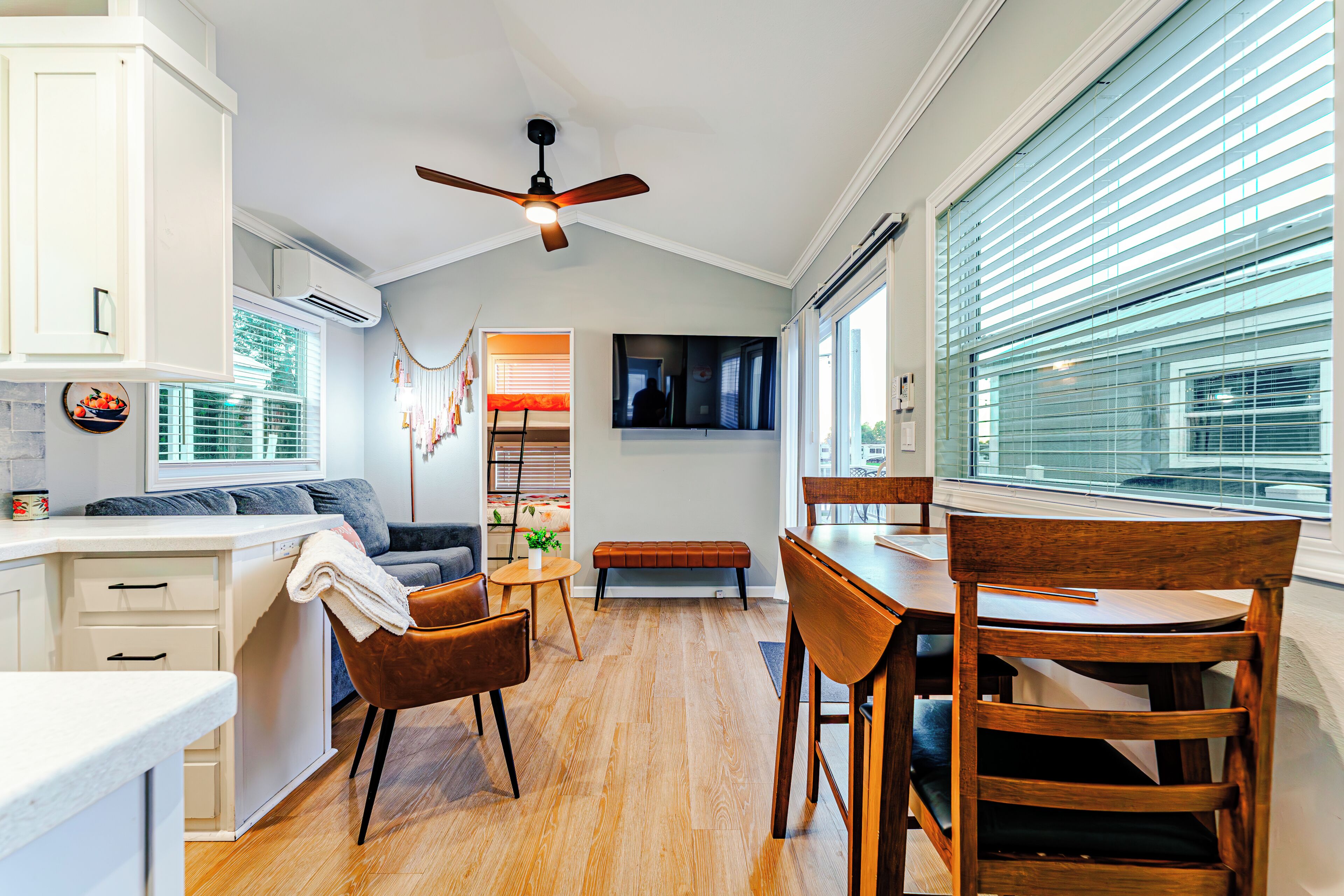 A modern kitchen with a dining area, wooden flooring, and a ceiling fan.