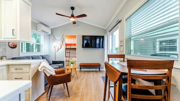 A modern kitchen with a dining area, wooden flooring, and a ceiling fan.