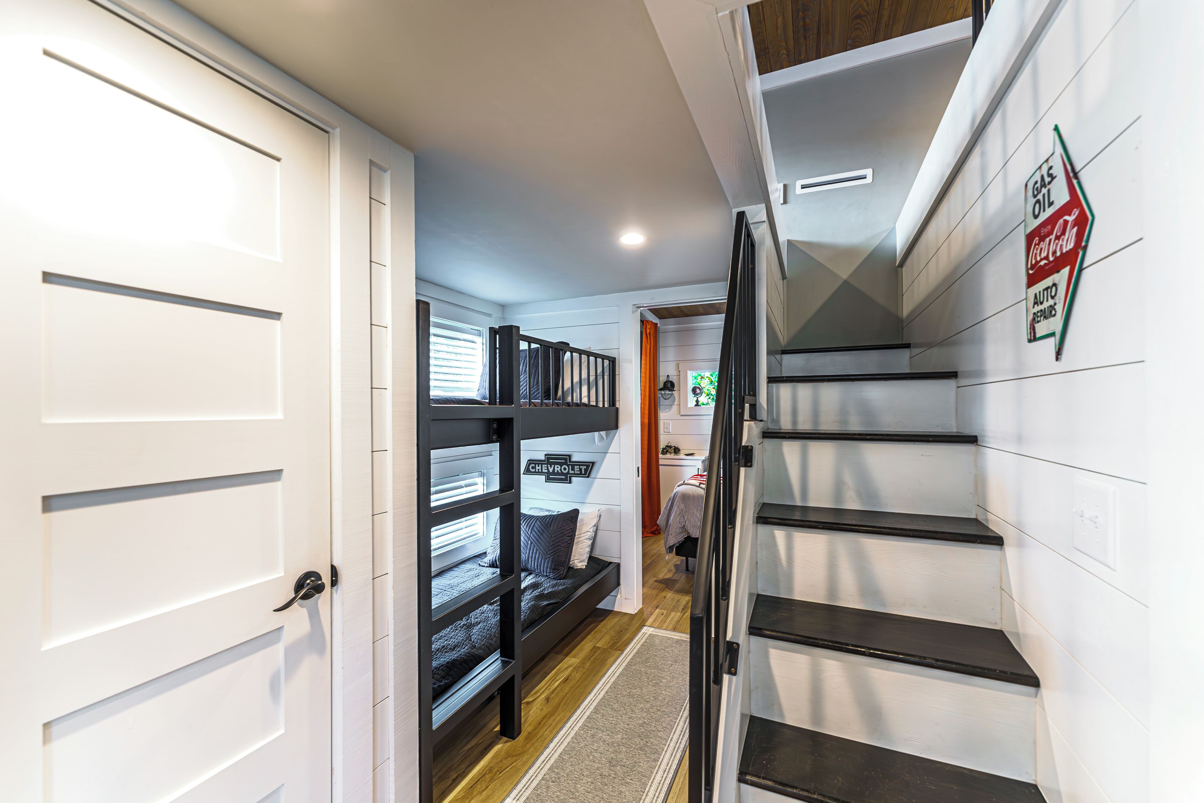 A hallway with a bunk bed, a staircase, and a wall sign indicating auto repair services.