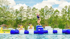 Ein Wasserpark mit aufblasbaren Attraktionen und einer Person, die von einer Plattform springt.